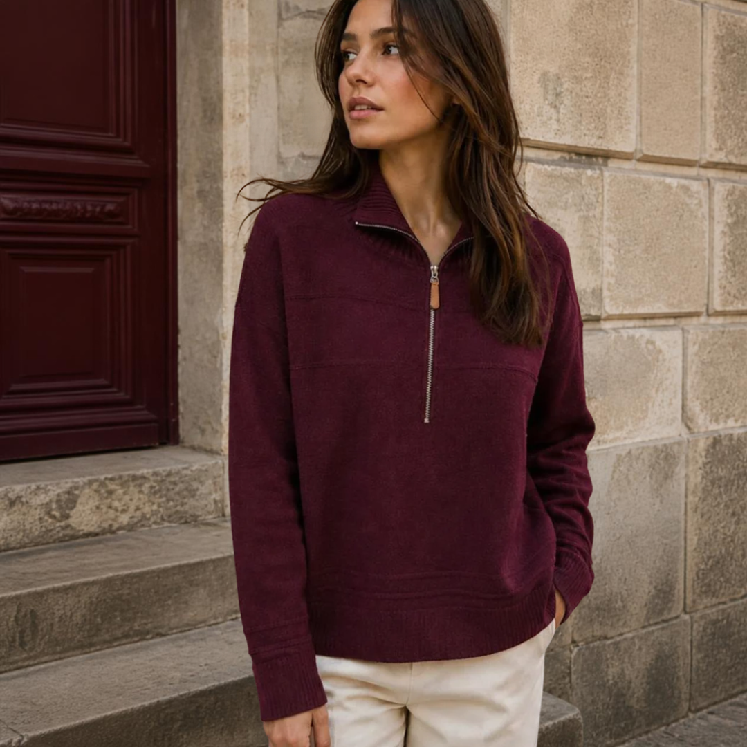 Model wearing KIDDING high-neck zip-up trucker sweater in wine colour with ribbed collar, cuffs, and hem, paired with cream trousers
