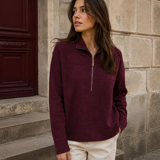 Model wearing KIDDING high-neck zip-up trucker sweater in wine colour with ribbed collar, cuffs, and hem, paired with cream trousers