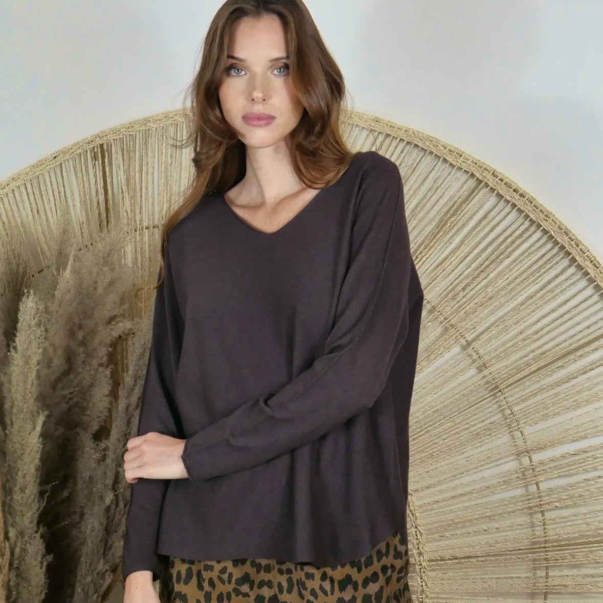 Woman wearing a dark gray long-sleeve top with a leopard print skirt against a neutral background