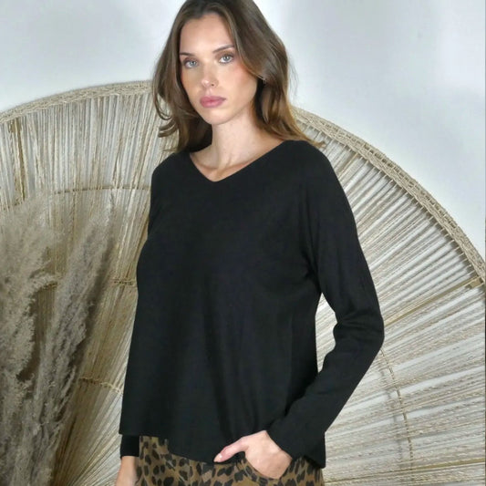 Woman wearing a black long-sleeve top with a neutral background