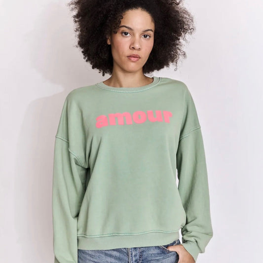 Person wearing a light green sweatshirt with pink text on a white background