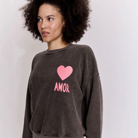 Person wearing a dark grey sweatshirt with a pink heart and 'AMOR' text on a white background