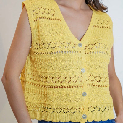 Yellow crochet vest worn by a person on a plain background