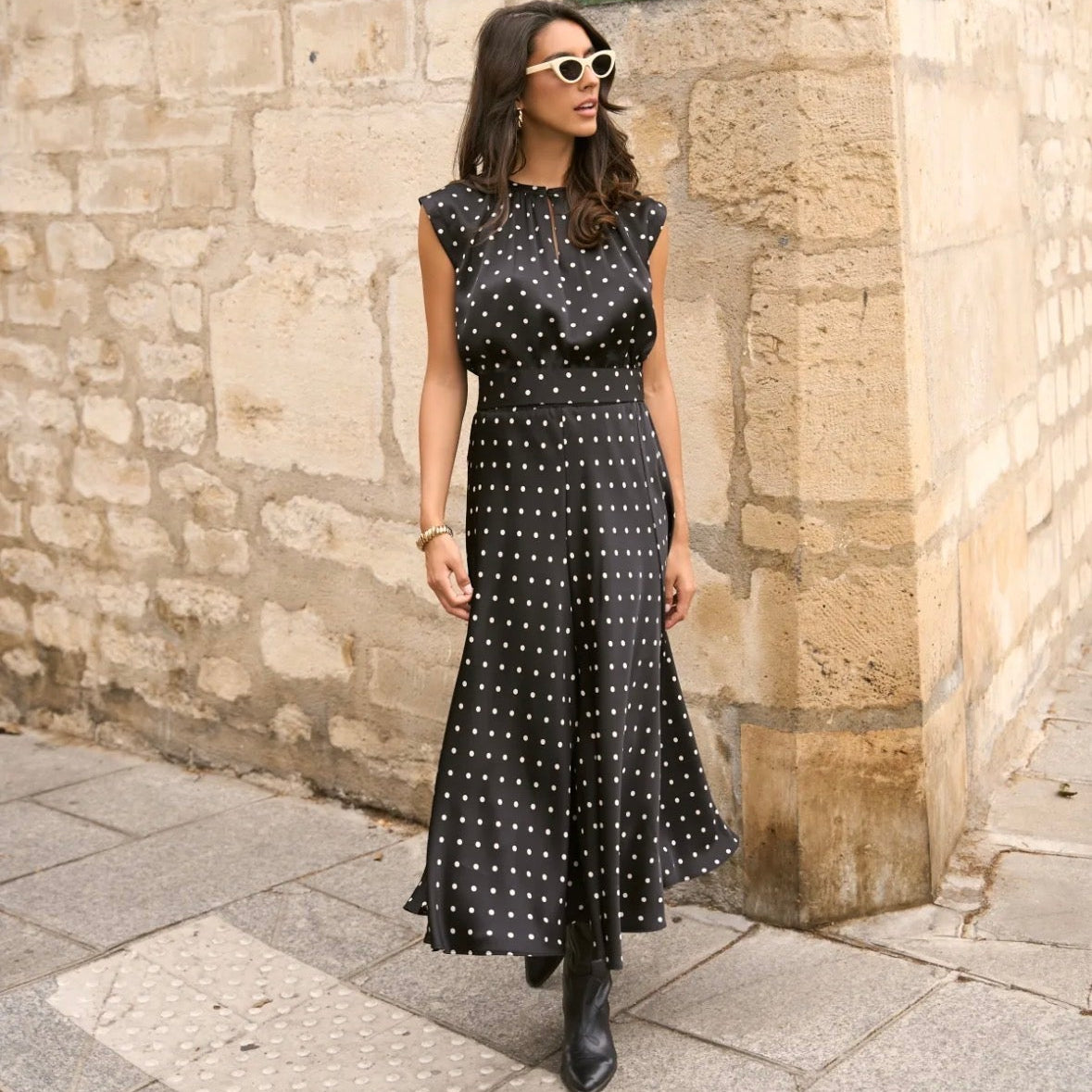 Model wearing KIDDING high-waisted black and white polka dot satin midi skirt with matching polka dot sleeveless top and black boots on a Paris street