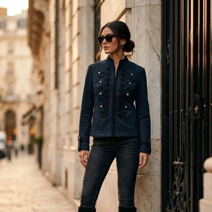 Model wearing KIDDING marine military jacket with black braided scroll frogging, gold dome buttons, Mandarin collar, and black piping paired with dark jeans and boots
