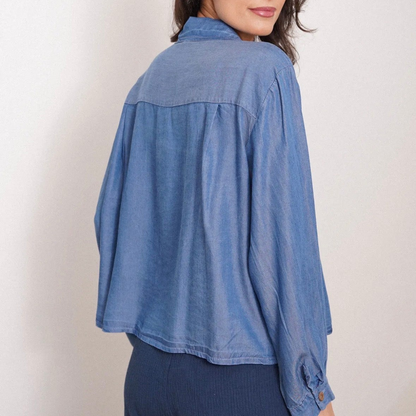 Woman wearing a blue denim shirt against a plain background