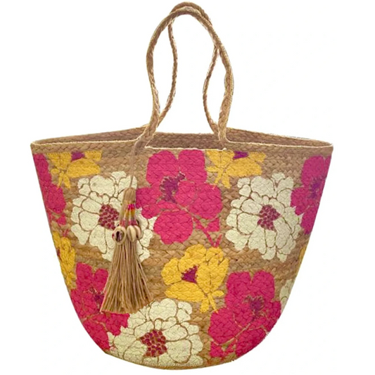 A beige-colored straw tote beach bag with multicolored floral patterns and a tassel detail.